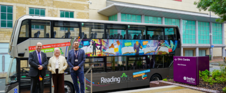 Three people in business attire pose beside a colorful Reading Books library bus outside a civic centre.','A double-decker library bus with vibrant banners reads 'Reading books' parked near a Civic Centre sign; three adults smile.','Library bus with mural advertising books stands in front of a modern building; three people pose for photo.','Purple Civic Centre sign and a modern Reading library bus with murals sit in a plaza, with three adults in front.