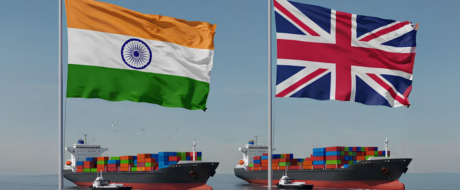 Two large cargo ships carrying colorful containers sail with Indian and British flags flying above.