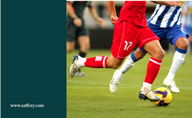 Action shot of soccer players' legs contending for the ball on a green field; a player in red kit (number 17) is near the ball.