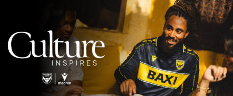 Promotional banner reading 'Culture Inspires' featuring a smiling man in a navy and yellow Oxford United jersey with club and Macron logos.