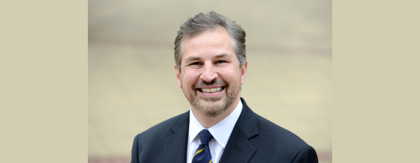 NEW - News item size 77 | Thames Valley Chamber of Commerce Professional headshot of a smiling man in a navy suit and blue tie outdoors against a neutral background.