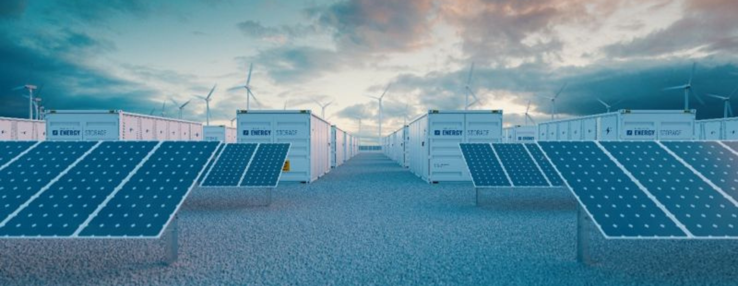 NEW - News item size 84 | Thames Valley Chamber of Commerce Rows of blue solar panels on concrete risers in a storage facility, with wind turbines visible in the cloudy sky behind them.