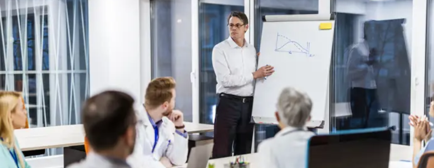 NEW - News item size 85 | Thames Valley Chamber of Commerce Man presenting a graph on a flip chart to colleagues in a modern conference room.