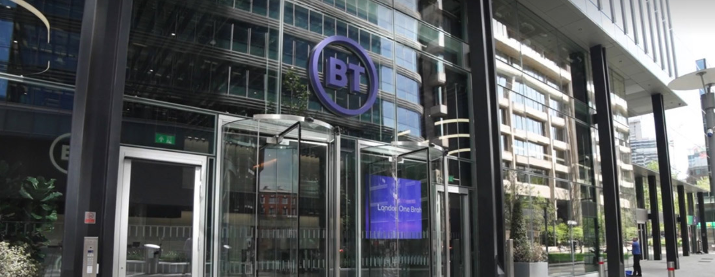 BT office building entrance with glass doors and a circular BT logo in a modern city setting.