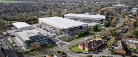 Aerial view of a business park with large white-roofed warehouse buildings and surrounding residential streets.