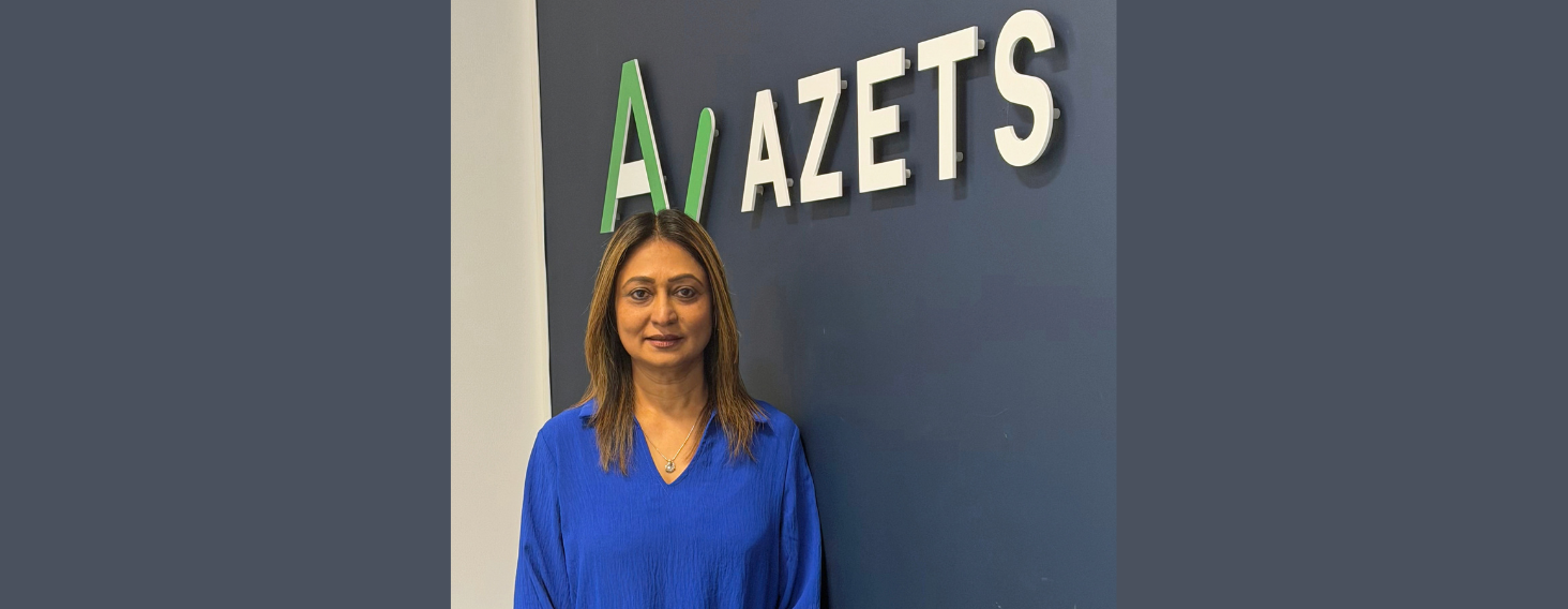 NEW - News item size 91 | Thames Valley Chamber of Commerce Portrait of a woman in a blue blouse standing in front of a dark blue wall with the company sign 'AZETS' above her left shoulder.