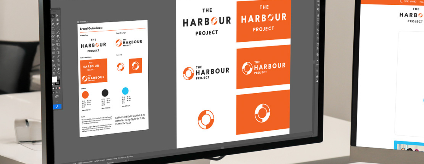 Two monitors show branding mockups for 'The Harbour Project' in orange and white, featuring the circular logo and layout sheets.