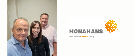 Three smiling professionals posing together beside the Monahans logo on the right in a neutral setting.