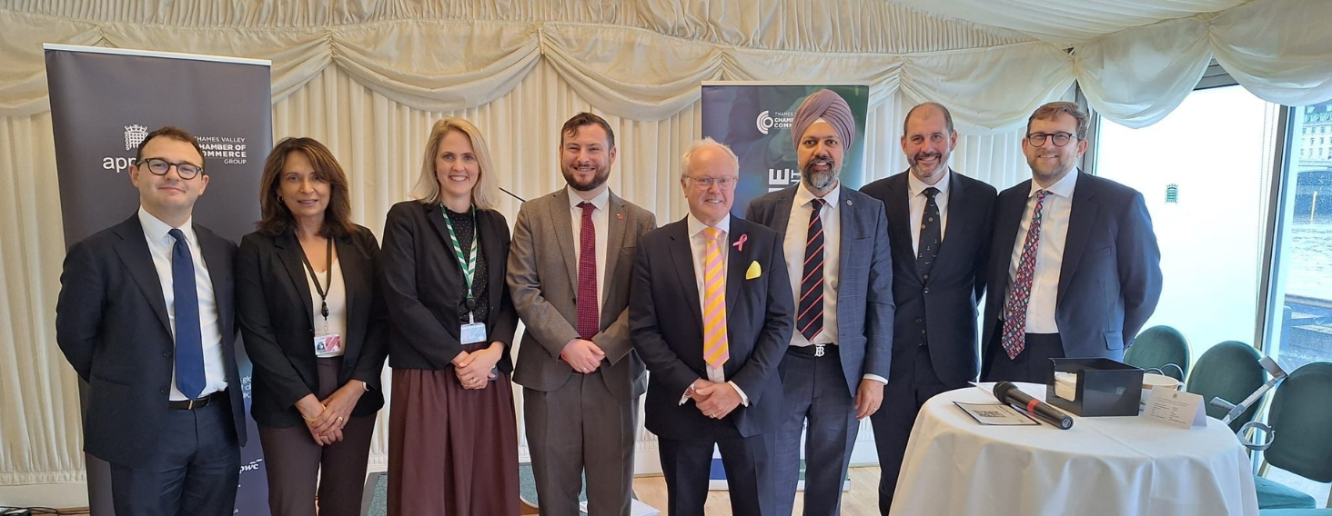 NEW - News item size - 2026-10-22T141823000 | Thames Valley Chamber of Commerce Group of eight professionals in business attire posing for a photo at a formal event, with banners and a table with a microphone nearby